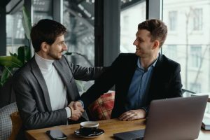 two-businessmen-shaking-hands-while-meeting-lobby